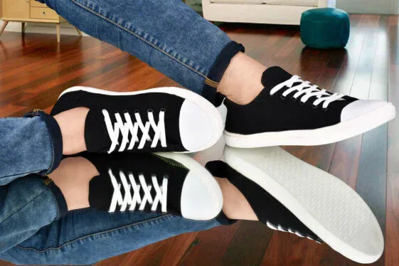 Sleek black canvas sneakers with white laces and a contrasting white sole, styled with blue denim jeans, displayed on a reflective surface. #black #blacklove #blacksneakers #buyblack #buynow #lowprice