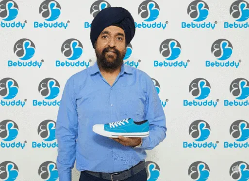 Brand owner holding a blue canvas shoe in front of a Bebuddy brand backdrop